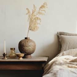a bed with pillows and a table with a vase and a candle