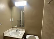 Thumbnail 8 of 17 - A bathroom with a toilet, sink, and mirror.