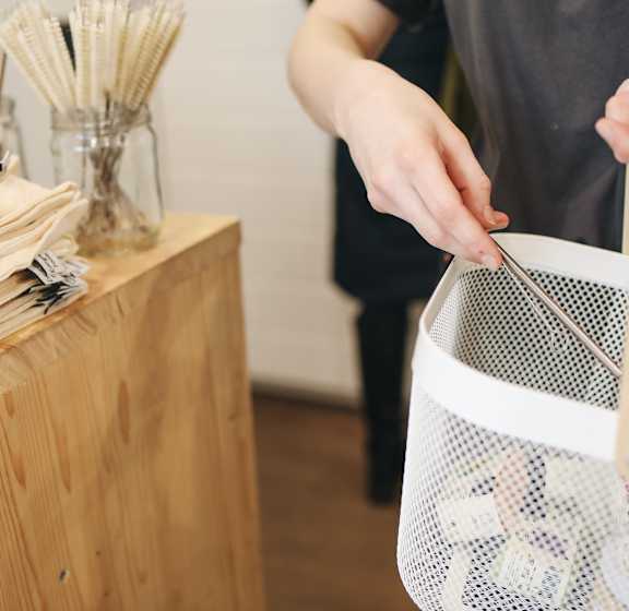 A person is holding a piece of pasta in a colander.