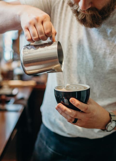 a man pouring coffee into a cup in a coffee shop