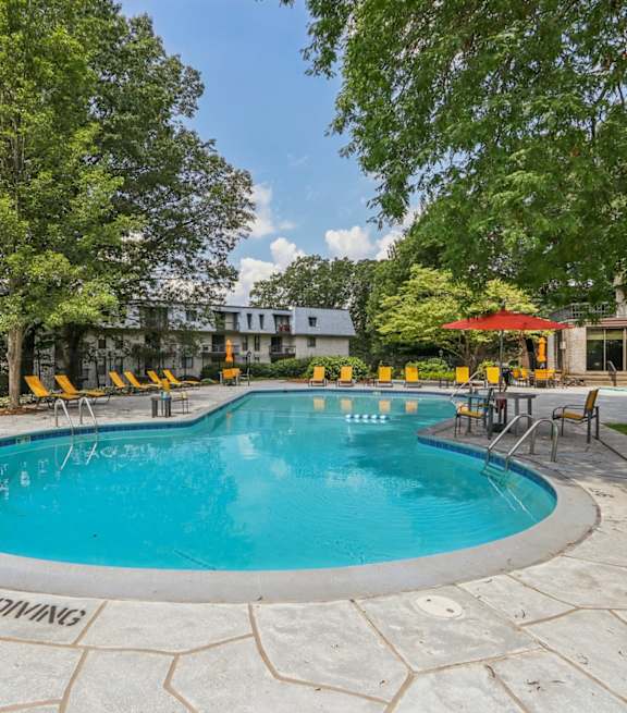 A round swimming pool surrounded by trees and chairs.