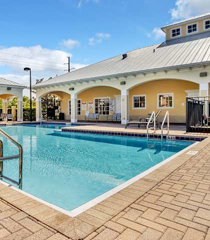 A pool with a metal ladder and a building in the background.