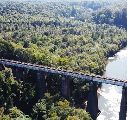 Aerial view of a large bridge spanning the Pacolet River, surrounded by dense green trees.