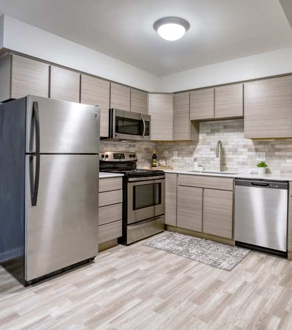 A modern kitchen with a stainless steel refrigerator and wooden flooring.