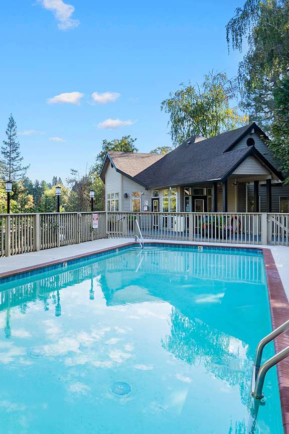 A small pool in a backyard with a house in the background.