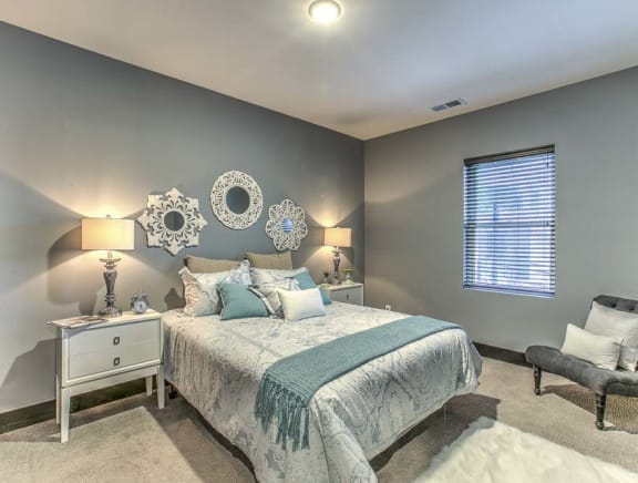 a bedroom with a bed, nightstands, and decorative mirrors on the wall