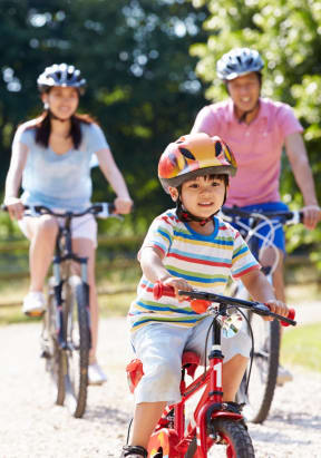 Young Family Riding Bikes Together Smiling