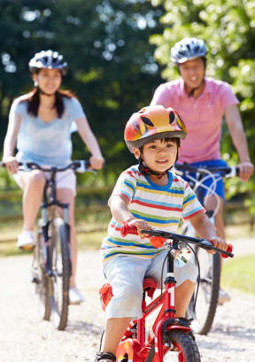 Young Family Riding Bikes Together Smiling