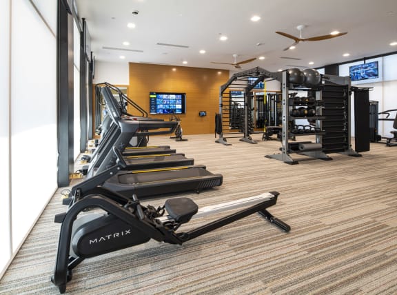 a gym with treadmills and other exercise equipment in a room with a window