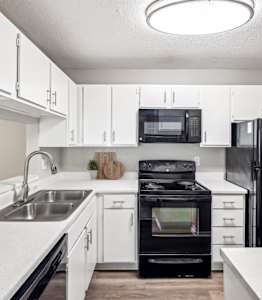 a kitchen with black appliances and white cabinets and a stainless steel refrigeratorat Chapel View, Chapel Hill North Carolina