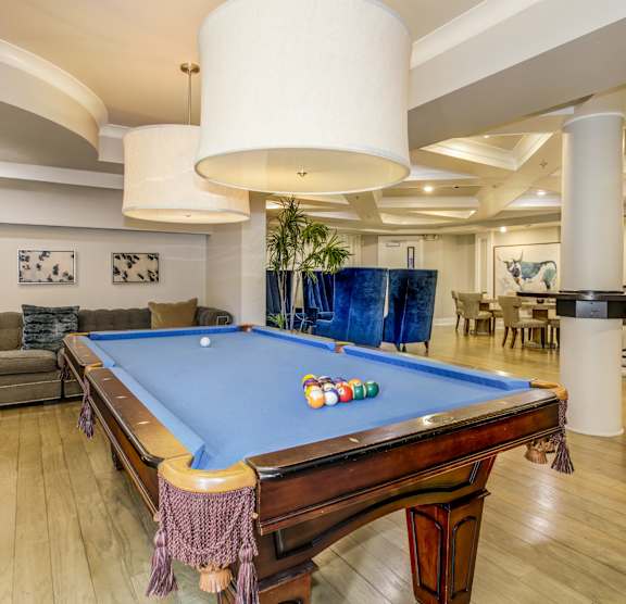 A pool table in a room with a couch and a bar. at Kensington Place Apartments, Woodbridge, Virginia