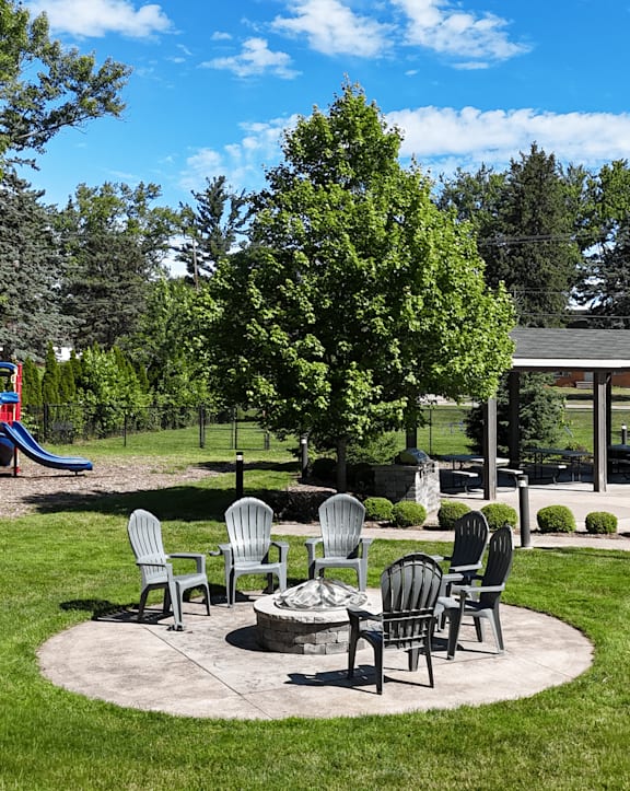 A park with a playground, chairs, and a fire pit.