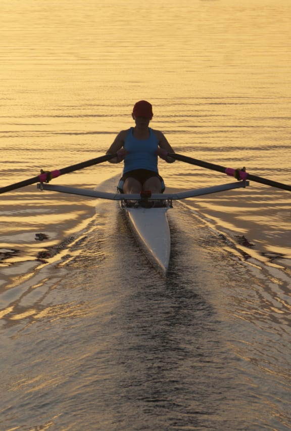 person kayaking into the sunset