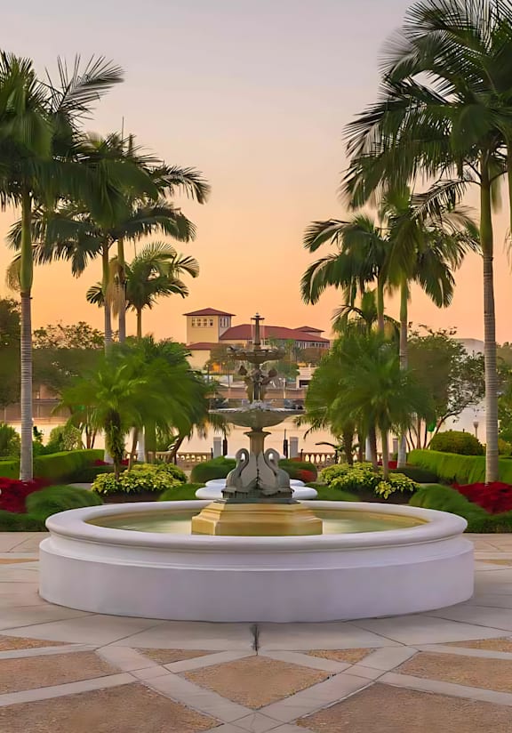 A beautiful fountain surrounded by palm trees and flowers.