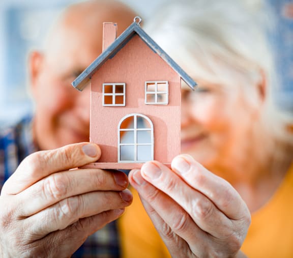 an older couple holding a toy house