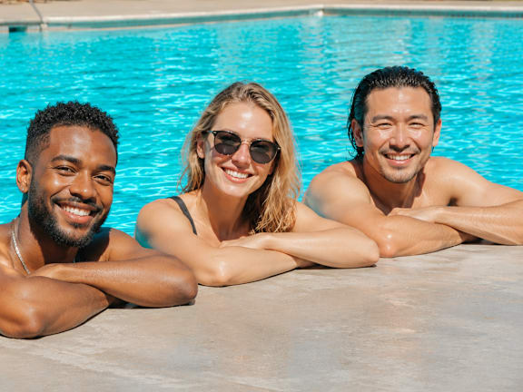 Four people sitting by a pool.