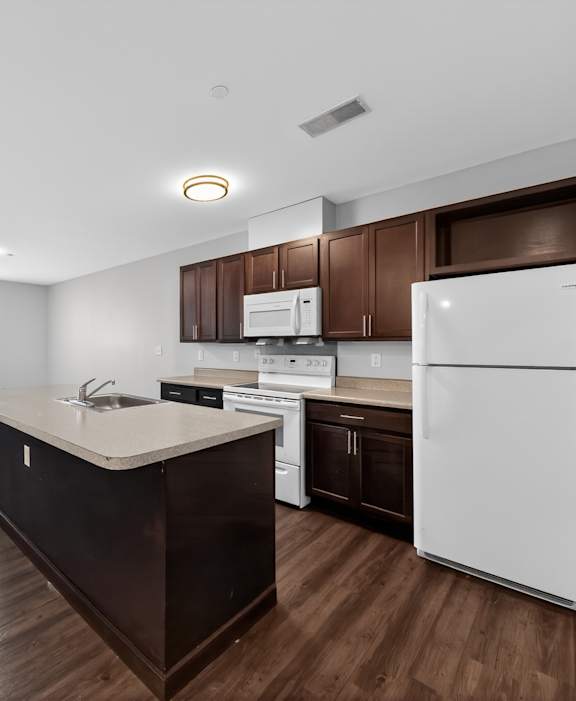 A kitchen with white appliances and brown cabinets.