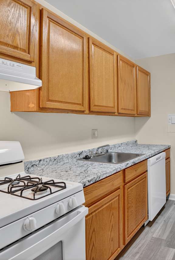 A kitchen with a white stove and wooden cabinets.