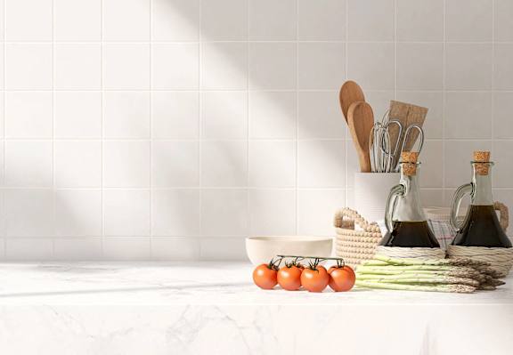 a white kitchen counter with tomatoes and other vegetables on it