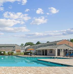 A large outdoor swimming pool surrounded by a brick patio.
