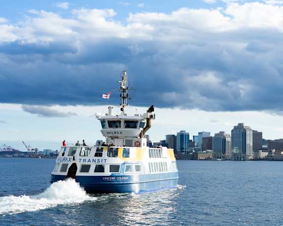A blue and white ferry boat is moving through the water.