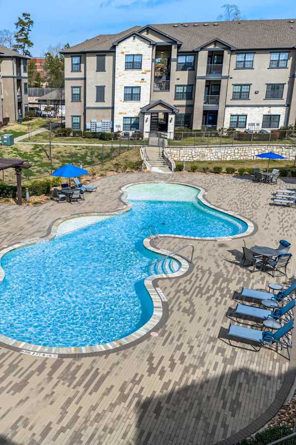 A large swimming pool with a wooden deck and lounge chairs.