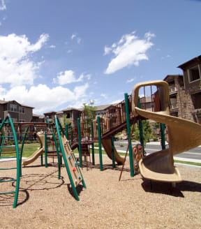 a playground with a slide and monkey bars in front of an apartment complex