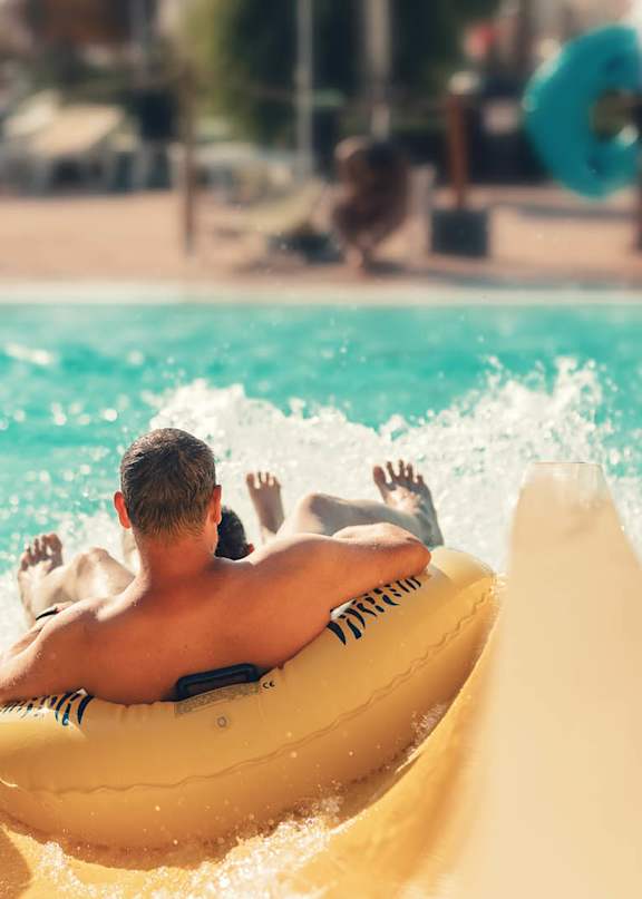 A man is riding a yellow tube down a water slide.