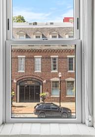 A black car is parked in front of a brick building with a garage door.