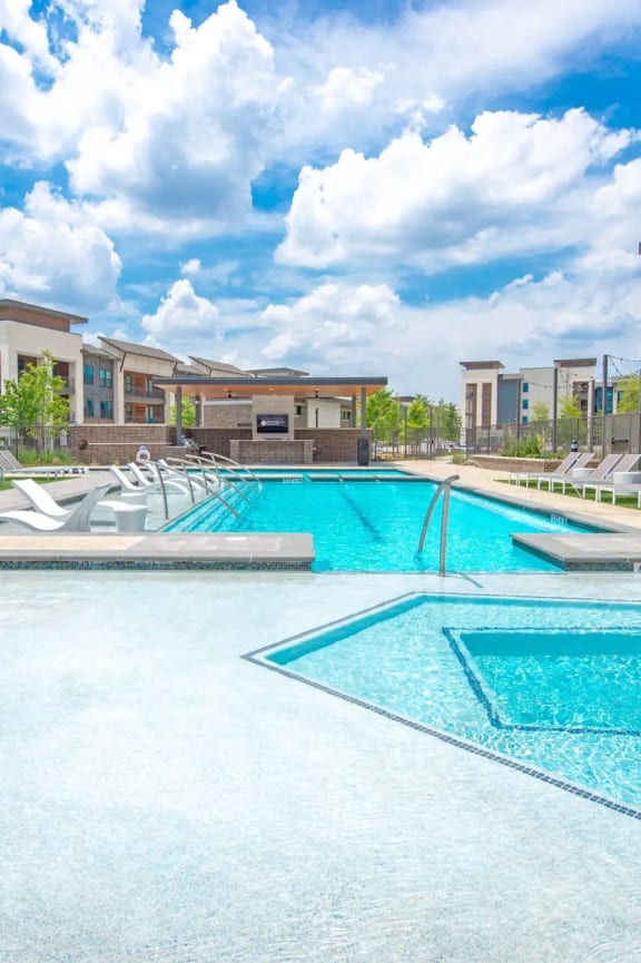 a large pool with lounge chairs in front of a building