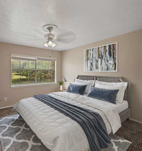 A bedroom with a large bed and a ceiling fan.