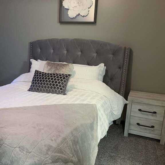 a bed with a white comforter and pillows in a small bedroom at North Pointe Villas Apartments, Lincoln, Illinois