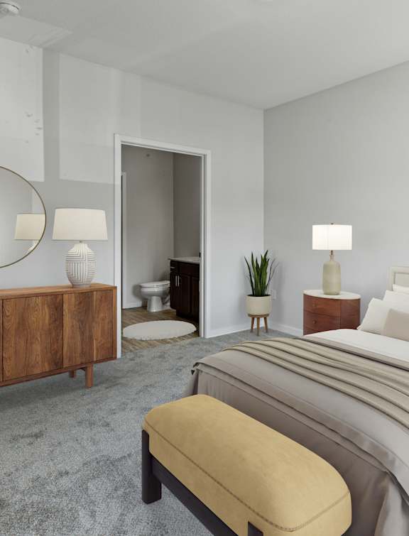A bedroom with a large bed, a bench, and a mirror.