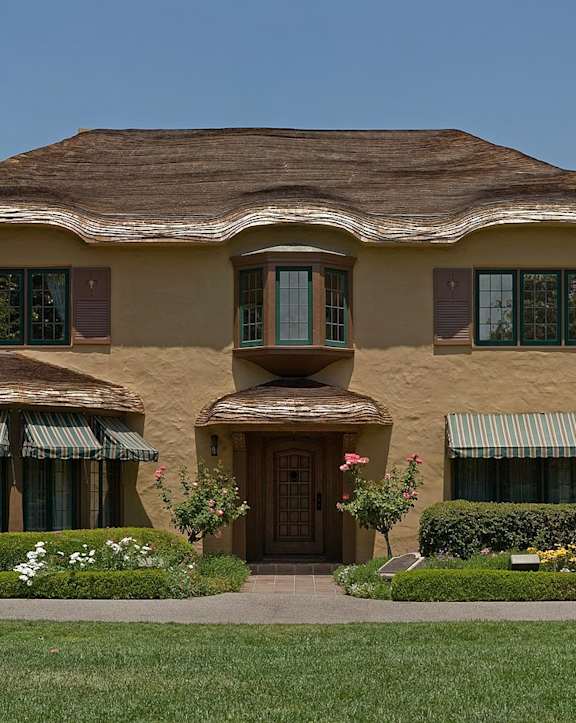 A house with a brown roof and a green lawn in front.