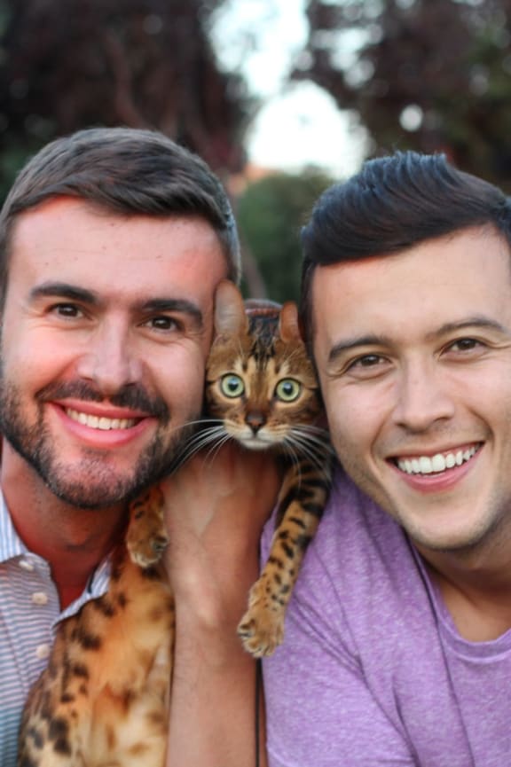 two men with a cat in the park