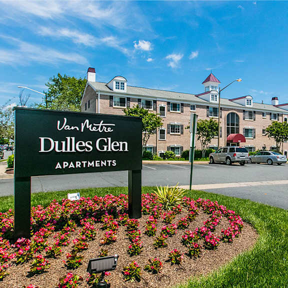 A brick building with a balcony and a tree in front. at Dulles Glen Apartments, Herndon, 20170
