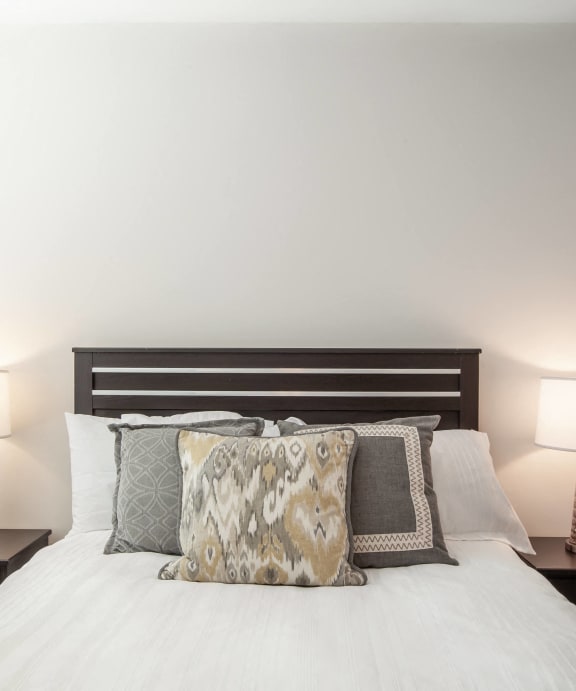 a bedroom with a bed with pillows and two lamps