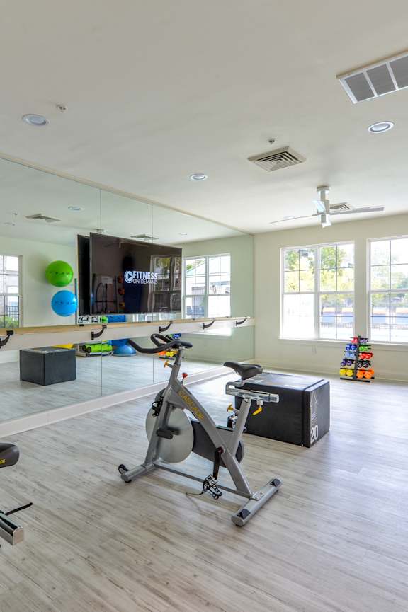 a workout room with treadmills and a tv