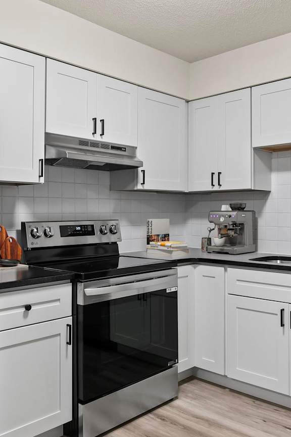 A kitchen with white cabinets and a black fridge.