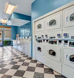 A laundromat with a checkered floor and rows of washers and dryers.