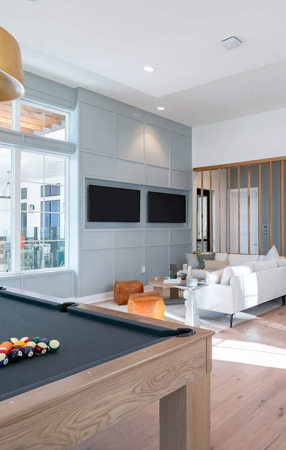 A billiard table is in the middle of a spacious room with a staircase on the right.