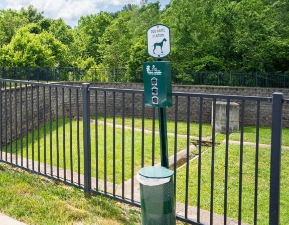 a black wrought iron fence with a green sign on it and a yard behind it