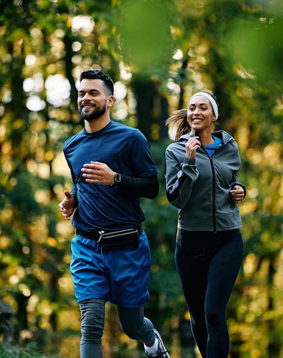A man and a woman are walking on a path in the woods.