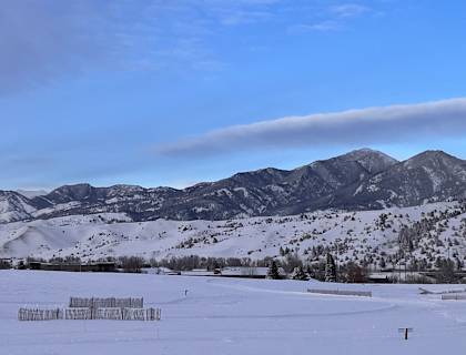 a snow covered field with mountains in the background