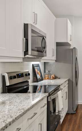 A kitchen with white cabinets and a painting hanging on the wall.