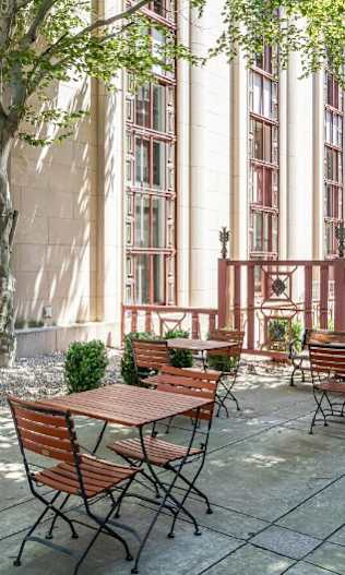 A patio with tables and chairs is surrounded by a building.