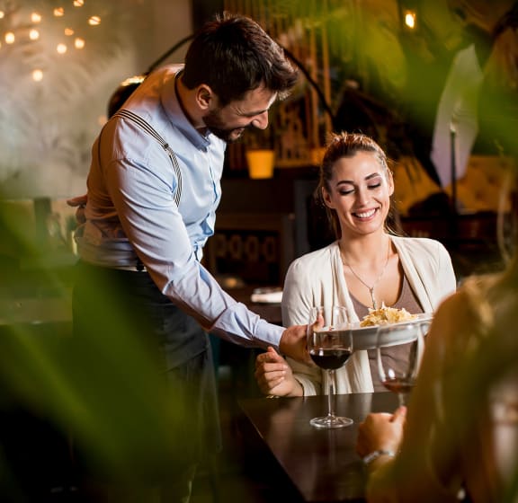 a man serving a glass of wine to a woman in a restaurant