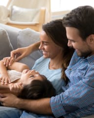 Young Family Laying on Sofa Together Smiling