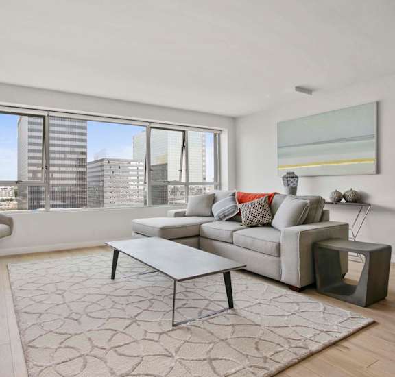 A modern living room with a grey couch and a large window at The View, Los Angeles, 90005