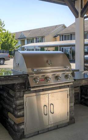 A covered outdoor kitchen area with a grill and sink.